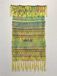 a yellow and blue piece of fabric hanging on a wall